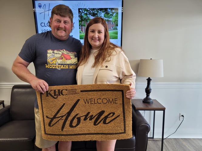 Elisabeth and Logan at their home closing holding a KHC welcome mat
