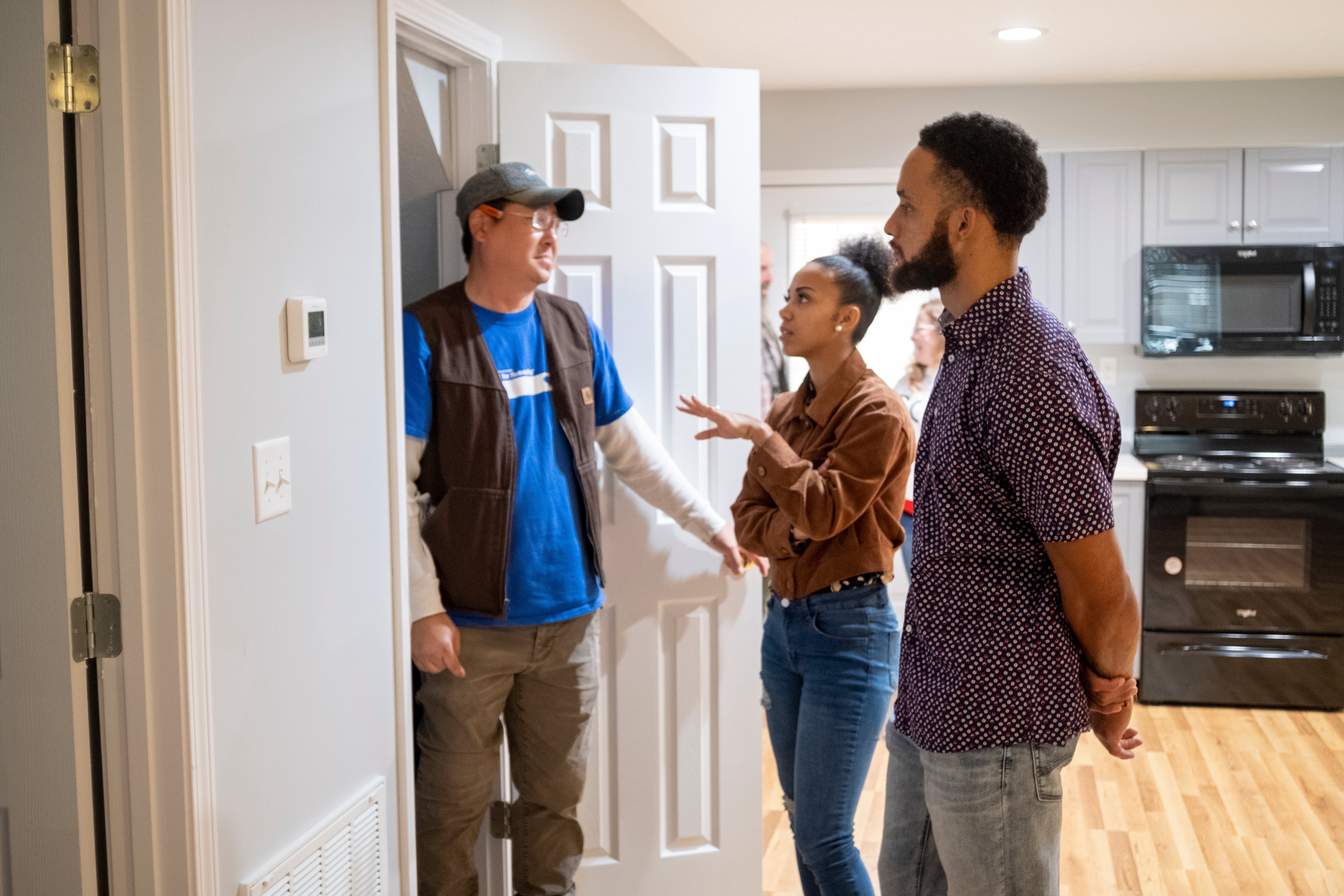 Chris and Kayla speaking with a Habitat worker inside their new home.