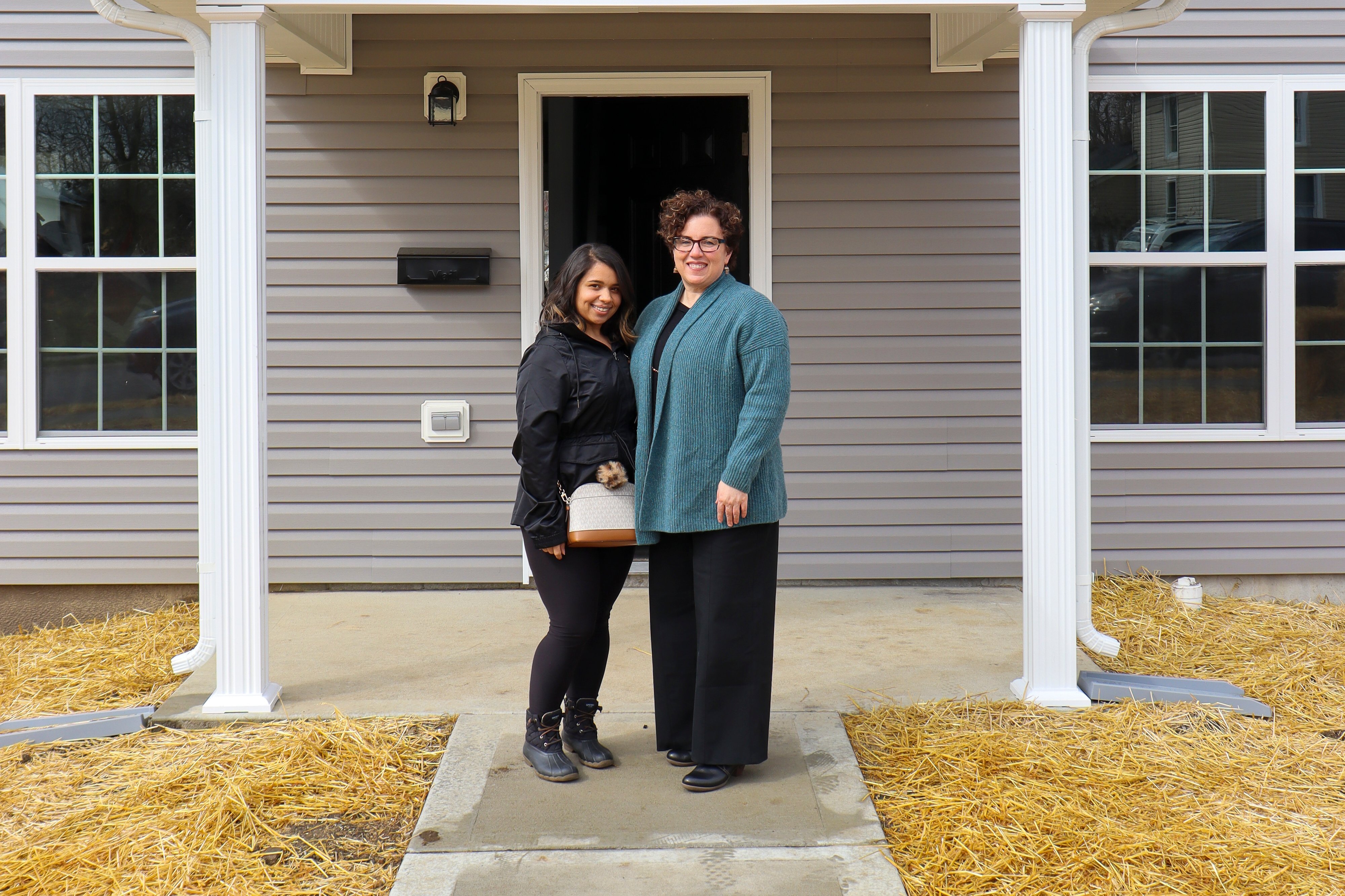 An FSS graduate poses with her KHC case manager in front of her new home